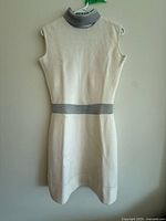 Front view of cream sleeveless knit dress with silver mock neck and waistband