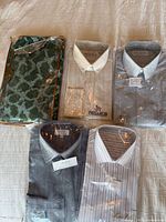 Six packaged men’s dress shirts arranged on bed
