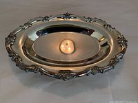 Angled view of oval meat tray showing ornate rim and juice well