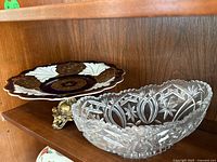 Compote on metal base beside cut glass bowl on shelf