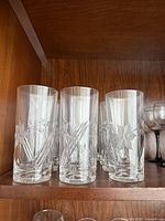 Front view of several etched floral highball glasses on shelf