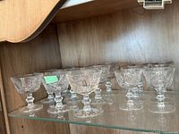 Twelve cut-crystal coupes on glass shelf
