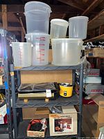 Overview of plastic canisters, electric grill, boxed burner on shelving