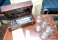 Open presentation case showing Lichfield glass ship sculpture, pitcher and four tankards on table