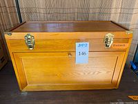 Front view of wooden machinist chest showing brass latches and drop-front panel