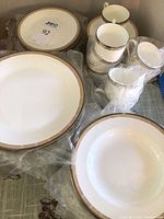 Stacked dinner plates, soup bowls, cups and saucers wrapped in plastic