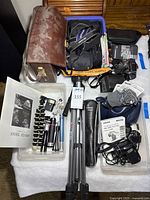 Overview of entire lot showing cameras, tripods, bags, accessories
