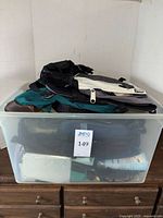 Clear bin containing multiple folded backpacks, bags, jackets