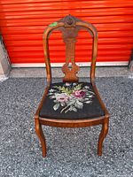 Front view of carved wood chair showing needlepoint seat