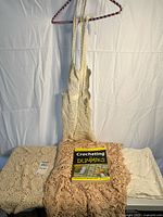 Overall lot showing apron on hanger, three folded linens and book