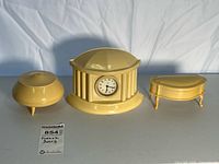 Three French Ivory pieces side by side: mantle clock, round jar, curved box