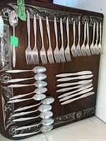 Full set laid out on wooden board showing forks, knives and spoons