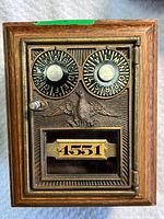 Front view of wooden post office box piggy bank showing brass combination door numbered 4551