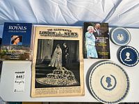 Group shot showing all items in lot: two Wedgwood plates, 1947 Illustrated London News, Royals book, sealed DVD set