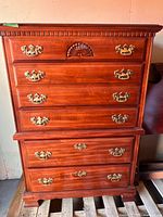 Front view showing six drawers, brass hardware, carved details