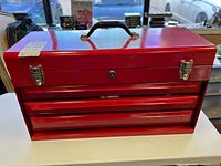 Front view of red three-drawer toolbox closed