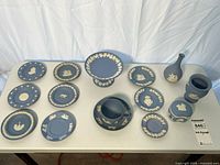 Full lot showing all 16 Wedgwood blue jasperware pieces on table
