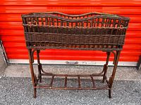 Front view of brown wicker plant stand showing basket, legs and support rungs