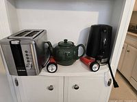 All items grouped on shelf: toaster, kettle, teapot, two flashlights