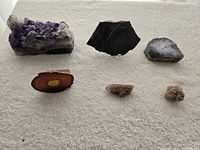 All six mineral specimens arranged on surface: amethyst cluster, three slices, chalcedony nodule, desert rose visible