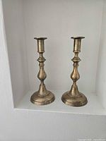 Front view of the two matching brass candlestick holders showing design and patina