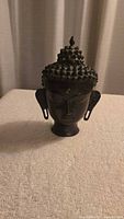 Front view of dark bronze Buddha head sculpture