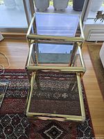 Top view of three stacked brass and glass nesting tables showing frames and glass surfaces
