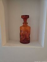 Front view of amber orange glass decanter with optic circle design and stopper