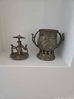 Vessel body and separate lid with tribal figures displayed side by side