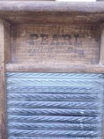 Close-up of Pearl and Canadian Woodenware branding on wood panel above glass insert