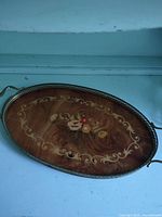 Full view of oval wooden tray showing marquetry and metal rim