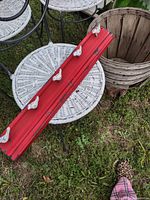 Red board with five white bird hooks resting on patio furniture