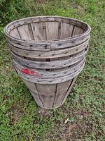 Weathered wooden bushel basket showing slatted sides, reinforcement bands and painted mark