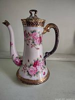 Full view of porcelain chocolate pot showing rose decoration, lid, handle and spout