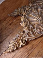 Close view of one plaque showing shell and leaf detailing, gold finish