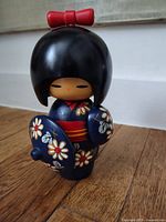 Full view of Kokeshi doll showing front floral kimono and red bow