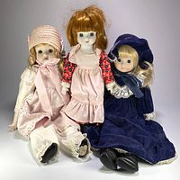 Group shot of all three porcelain fashion dolls seated