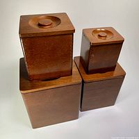 Four wooden canisters stacked showing lids and knobs