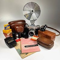Full bundle showing camera with flash, cases, filters, manuals and accessories