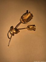 Full view of gold-tone rose brooch showing both blooms and stem