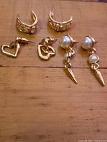 All three pairs of gold-tone post earrings displayed on wooden surface