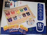 Front of retail box showing wooden magnetic maze puzzle toy, age recommendation 18+ months