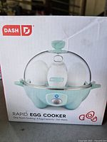 Front of retail box showing Dash Rapid Egg Cooker, mint green model, 6-egg capacity, 360 W