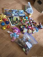 Overview of entire lot showing DVDs, pencil crayons, loose toys, flash cards, plush doll, bag of dinosaurs