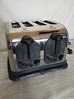 Front view showing dual control panels, levers, buttons, dials and crumb trays