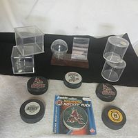 Group shot of six pucks, Franklin micro puck in package, and six display cases