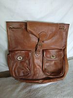 Front view showing flap, buckle, two turn-lock pockets