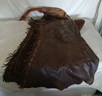 Full view of chaps showing leather, fringe, and zipper