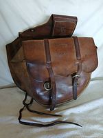 Front view of brown leather Mike Gano saddle bag showing flap pockets and buckle straps