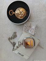 Both pocket watches with chains and packaging visible